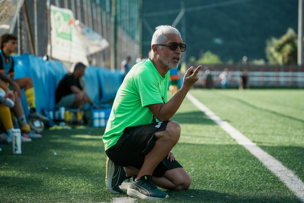 Un entrenador agachado al costado de la cancha le habla a sus jugadores