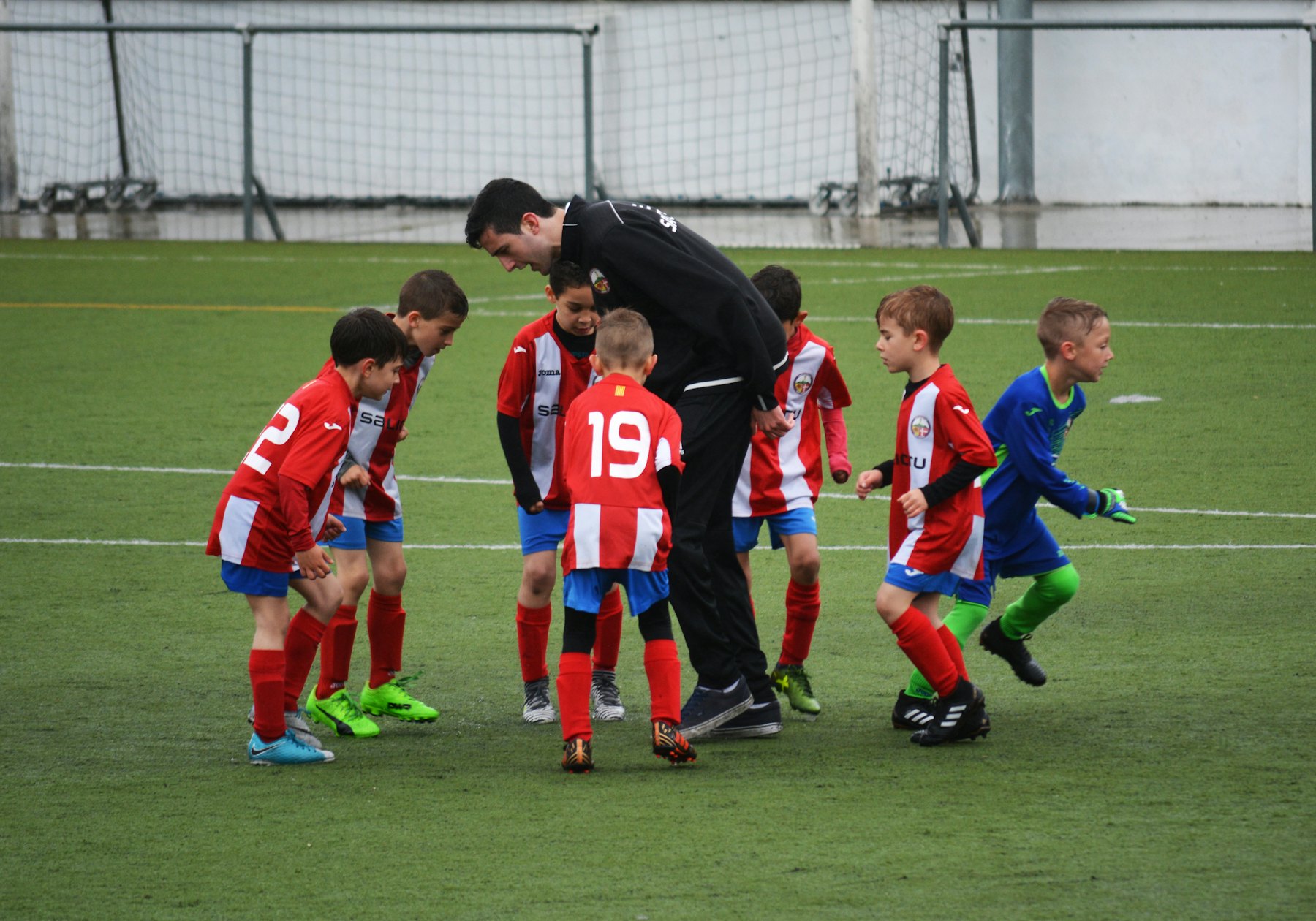 Un entrenador reúne a un grupo de chicos en la cancha antes de un ejercicio